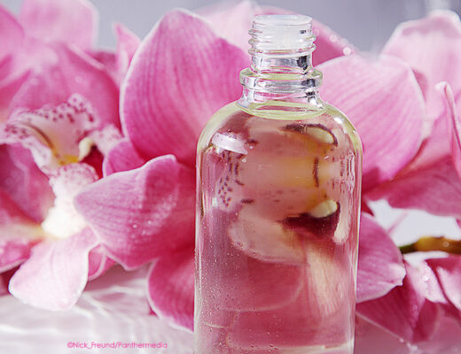 Massageöl für Abhyanga vor rosa Orchideen